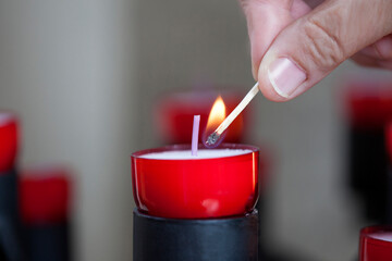 Female mature woman burning candle light in church