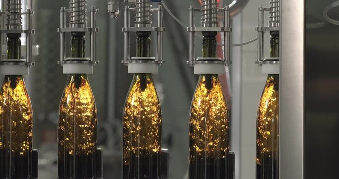 Wine bottling process. Filling bottles with red wine by the machine. Slow motion