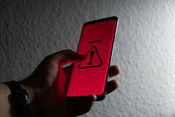 Symbol for the national warning day in Germany, 2022. Hand holds a mobile phone with the German text "Warntag 8. Dezember" (warning day on December 8th).