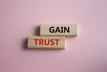 Gain trust symbol. Wooden blocks with words Gain trust. Beautiful pink background. Business and Gain trust concept. Copy space.