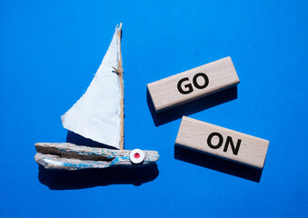 Go on symbol. Wooden blocks with words Go on. Beautiful blue background with boat. Business and Go...