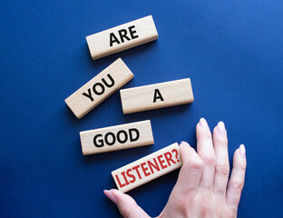 Listening skills symbol. Wooden blocks with words Are you a good Listener. Beautiful deep blue background. Businessman hand. Business and Are you a good Listener concept. Copy space.