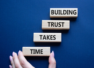 Building Trust takes Time symbol. Wooden blocks with words Building Trust takes Time. Beautiful deep blue background. Businessman hand. Business and Building Trust takes Time concept. Copy space.