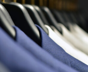 Suits in boutique. Merchandising of elegant suits in clothing store. Product fashion on clothing hangers. 