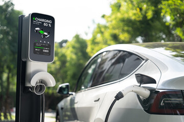 EV electric car charging in green sustainable city outdoor garden in summer. Urban sustainability...