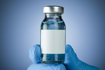 Hand in blue medical gloves holding a vaccine vial with blank white space for text. Healthcare concept with copyspace for text.