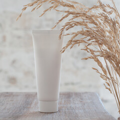 white tall jar for cosmetics on a wooden table decorated with dried flowers