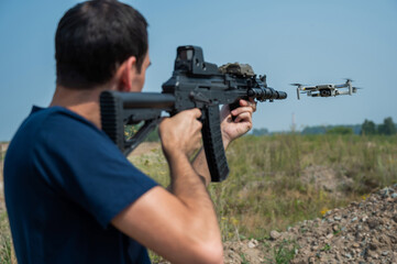 Man aiming to shoot a rifle at a flying drone outdoors. 