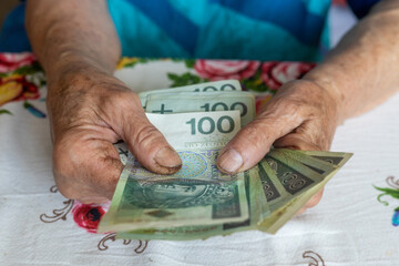 An old woman holds 100 Polish zloty banknotes in her hands, Polish money, Concept, Pension,...