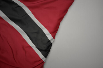 big waving national colorful flag of trinidad and tobago on the gray background.