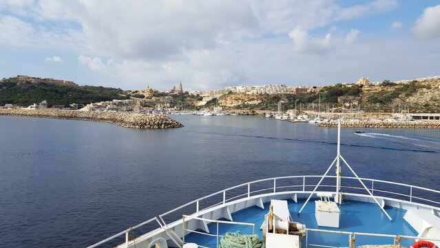 A sailboat glides across the sparkling blue lake, its white sails billowing in the wind..