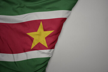 big waving national colorful flag of suriname on the gray background.