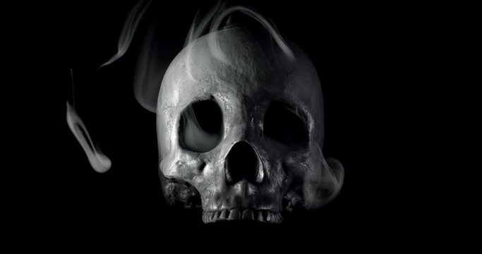 Smoke slowly creeping through the eye sockets of a terrifying human skull, haunted spirt, or frightening ghost for Halloween or other spooky scene.