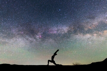 Woman silhouette dancing in the night, on the bright Milky Way Galaxy background.