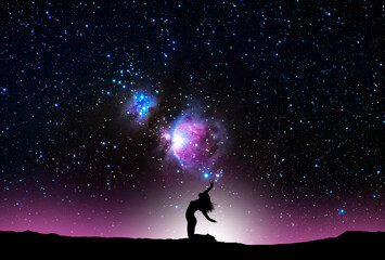 Woman silhouette dancing in the night, on the bright Orion Galaxy background.