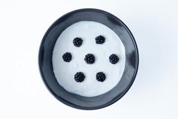 Tempting bowl with greek yogurt and blackberries on a white background