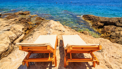 Coastal summer landscape - view of the beach loungers on a rocky seashore, on the island of Hvar, the Adriatic coast of Croatia