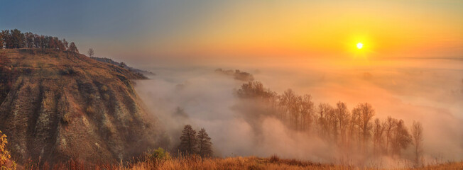 Fototapeta premium Autumn sunrise landscape, panorama, banner - view of a river valley covered with fog in the light of the sunrays, the northeast of Ukraine