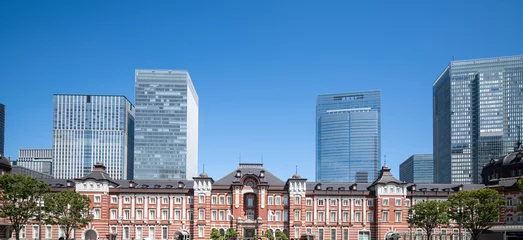 Foto op Plexiglas exterior view of Tokyo station from above he tracks in Tokyo, Japan on a sunny and partly cloudy day with skyscrapers in the background along with the Tokyo skyline © Davslens Photography