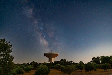 Giant space observatory with a milky way in the background next to a starry sky