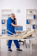 Old male doctor examining skeleton in the clinic