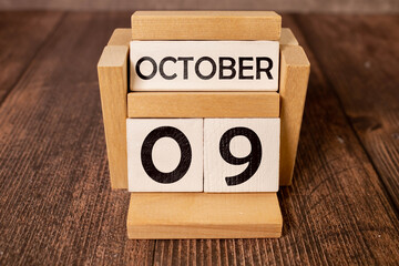 Cube shape calendar for October 09 on wooden surface with empty space for text.