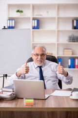 Obraz premium Old male employee working in the office