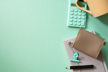 Notebook, calculator, clip, mug cup, pouch on green desk background. flat lay, top view. workspace