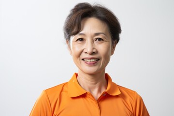 Fototapeta premium Medium shot portrait photography of a Vietnamese woman in her 50s wearing a sporty polo shirt against a white background