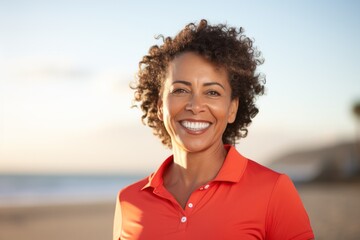 Portrait photography of a Peruvian woman in her 50s wearing a sporty polo shirt against a beach background
