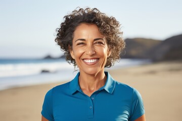 Portrait photography of a Peruvian woman in her 50s wearing a sporty polo shirt against a beach background