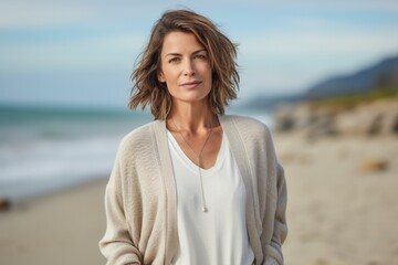Lifestyle portrait photography of a serious French woman in her 40s against a beach background - Powered by Adobe