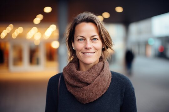 Group portrait photography of a Swedish woman in her 40s wearing a cozy sweater against a modern architectural background