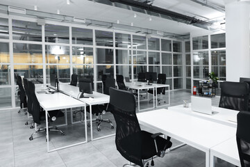 Stylish interior of open plan office. Workspace with computers, tables and chairs