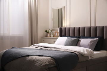 Comfortable bed with pillows and bedding in stylish room. Interior design