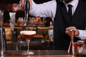 Bartender preparing Espresso Martini at bar counter, closeup. Alcohol cocktail