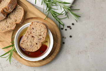 Bowl of organic balsamic vinegar with oil served with spices and bread slices on beige table, flat lay. Space for text