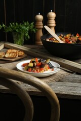 Delicious ratatouille served with bread on wooden table