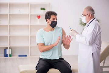 Obraz premium Young male patient visiting old male doctor in vaccination conce