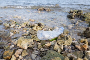 crashing sea waves carrying plastic drink bottle waste. the ecological concept of going green to reduce the use of plastic bottles which are difficult to recycle