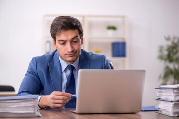 Young male employee and too much work in the office