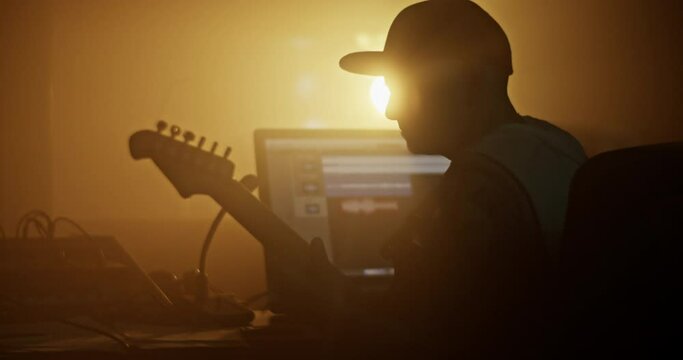Man in cap playing rock music on guitar in studio