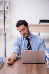 Young male employee suffering at workplace