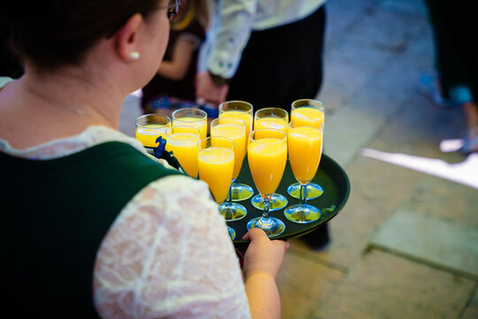 Bedienung mit einem Tablett Orangensaft und Sekt