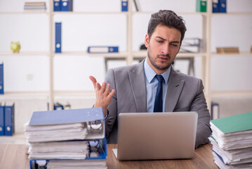 Young male employee and too much work in the office