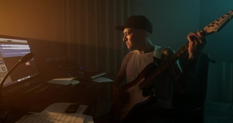 Man in cap playing rock music on guitar in studio