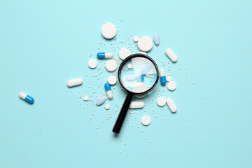 Magnifier with pills on blue background