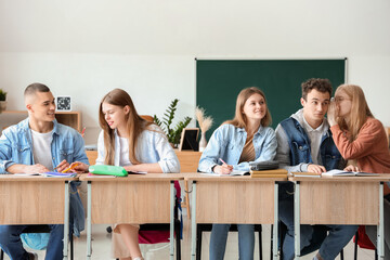 Students sitting and gossiping with his classmates in classroom
