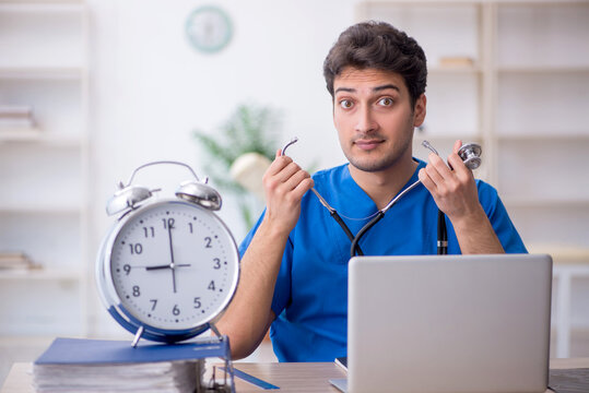 Young male doctor in time management concept