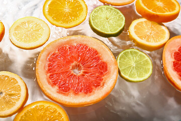 Different citrus fruit slices in water on white background